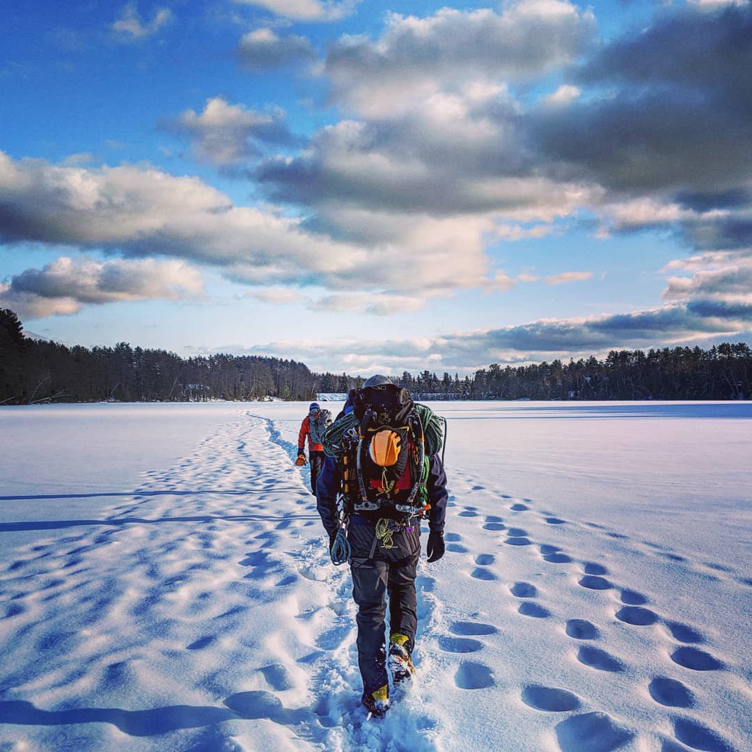 Hiking on the safe line across a frozen lake after an ice climbing day. Ontario, Canada