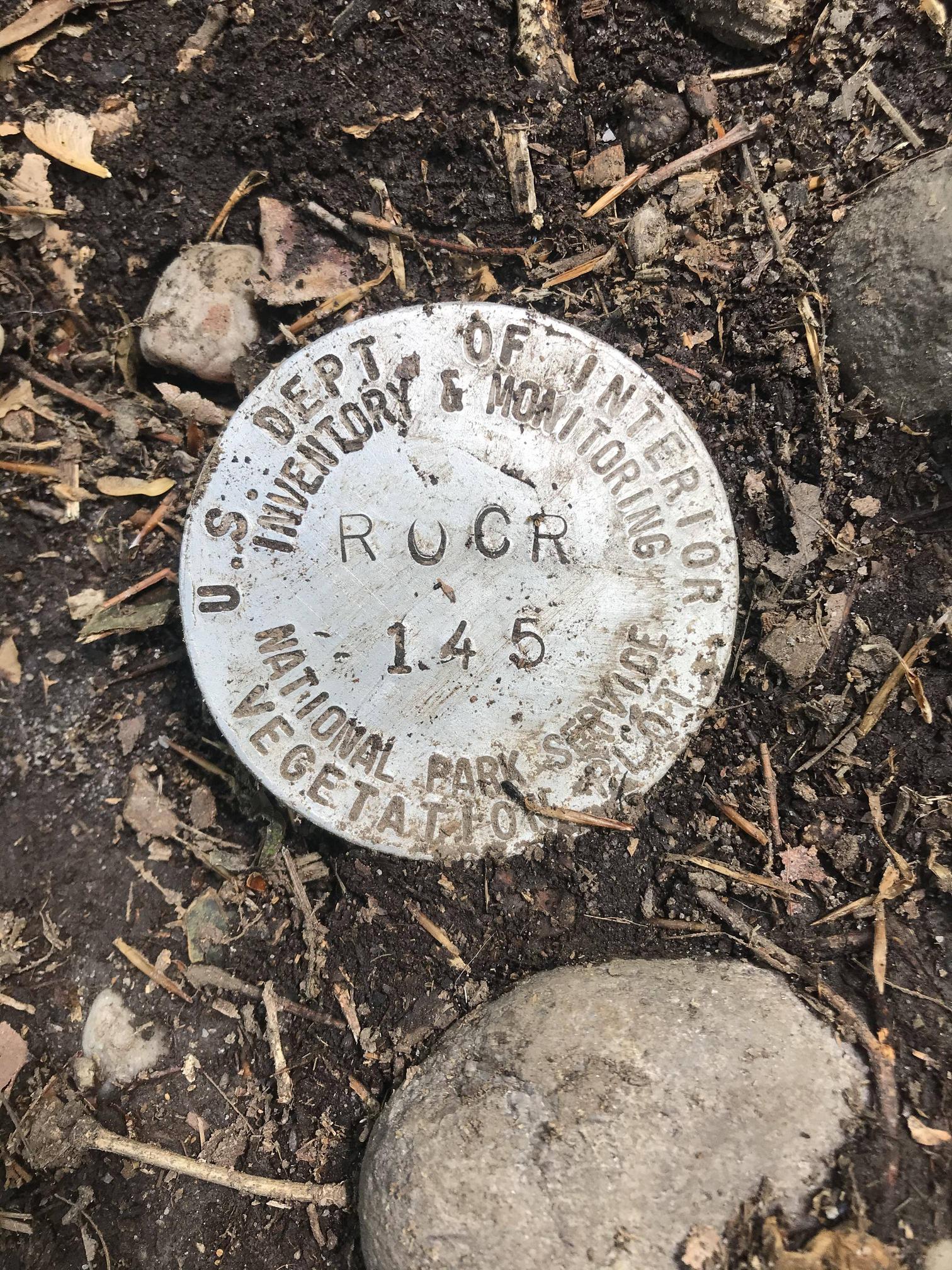 Small metal circle in the ground. Found in a hiking trail. It looks like the lid to something.